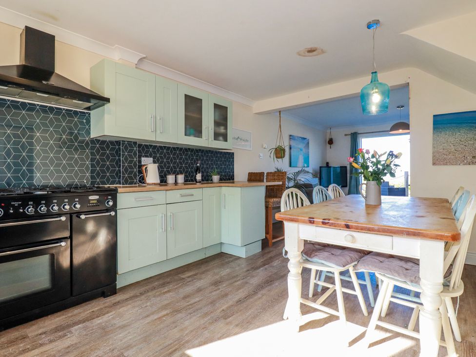 A kitchen with cabinets and a dining table at 3A Grannys Lane Perranporth