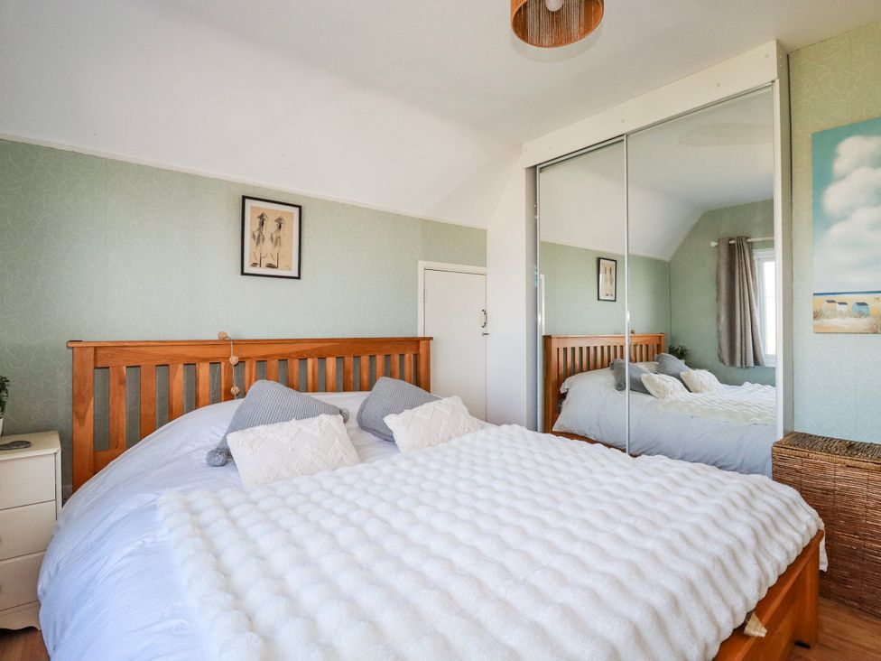 A bedroom with a bed and mirror at 3A Grannys Lane in Perranporth