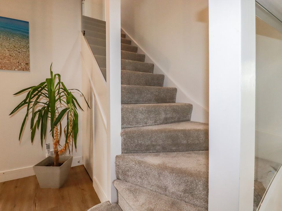 A staircase with a potted plant and wall art at 3A Grannys Lane in Perranporth