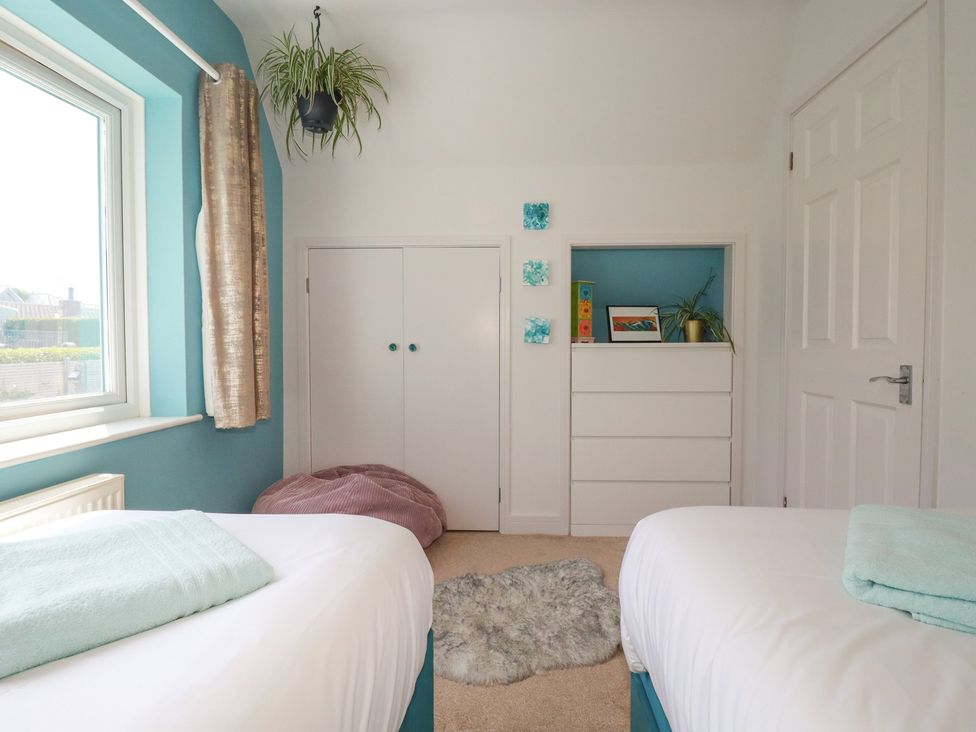 A bedroom with two beds and a closet at 3A Grannys Lane in Perranporth