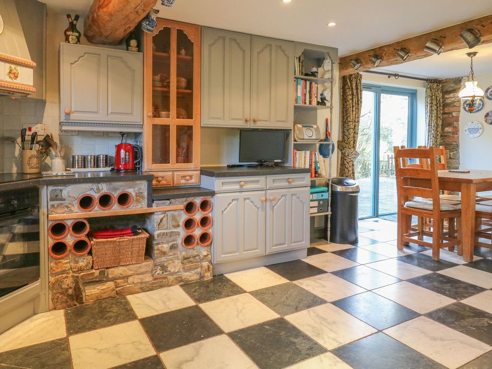 A kitchen with cabinets and a dining table at Pillars in Barnstaple