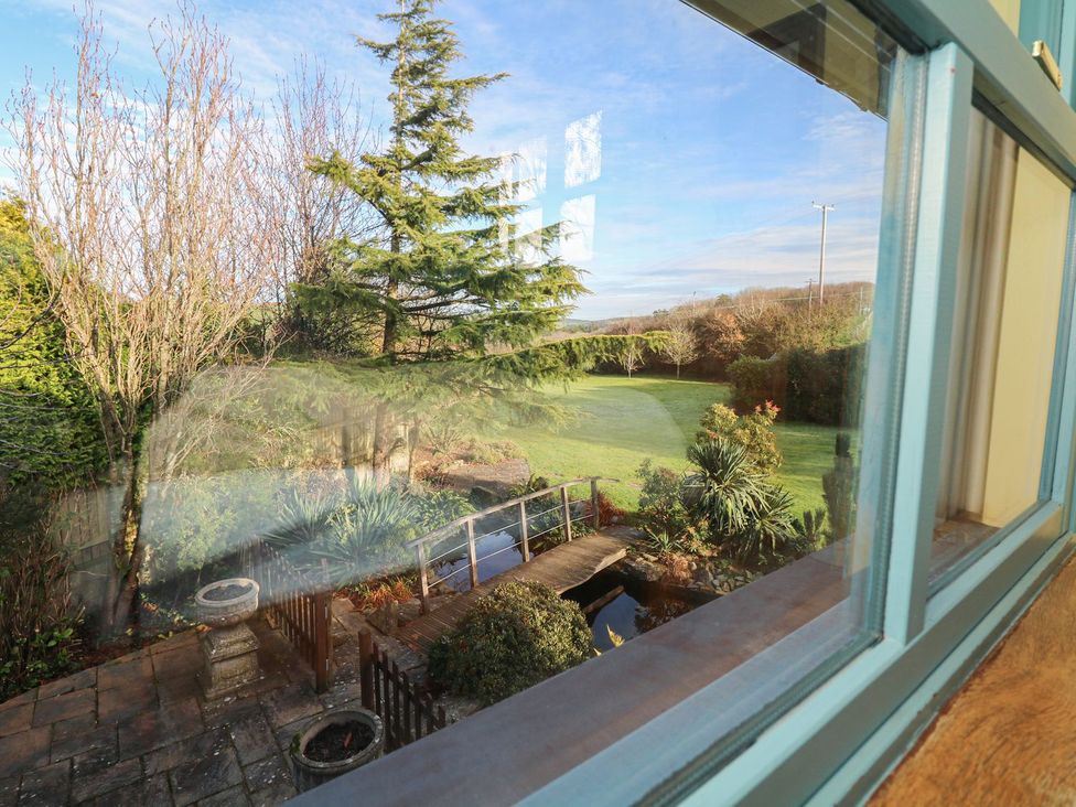 A garden view with trees and a pond at Pillars in Barnstaple