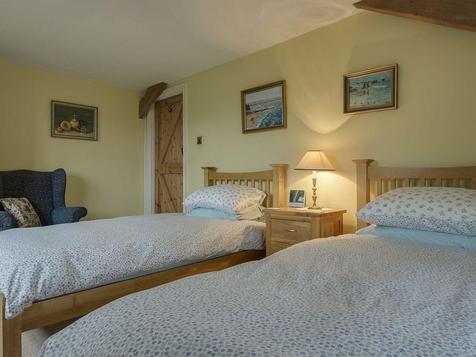 A bedroom with two beds and a chair at Pillars in Barnstaple