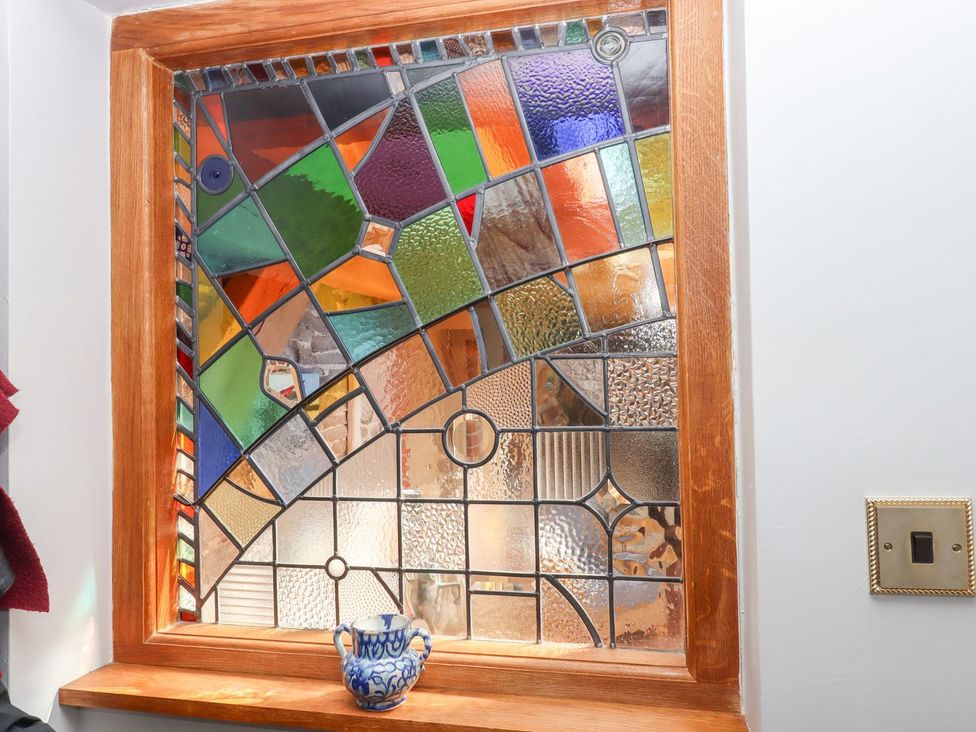 A stained glass window with colorful panels and a blue pottery piece at Pillars Barnstaple