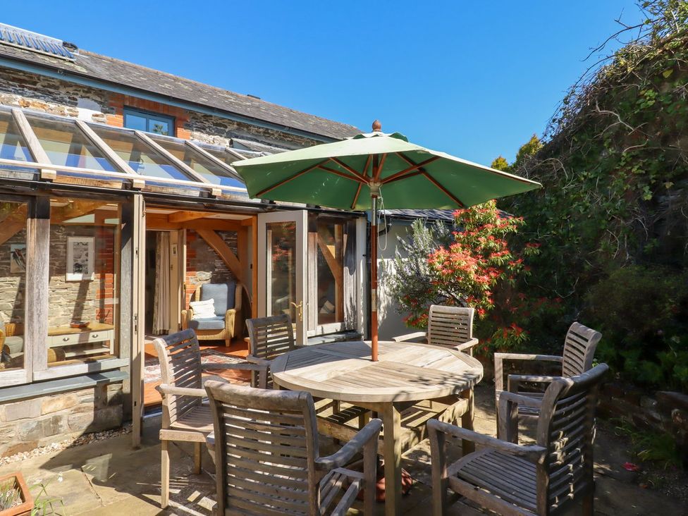 A garden with a table and chairs under an umbrella at Pillars in Barnstaple