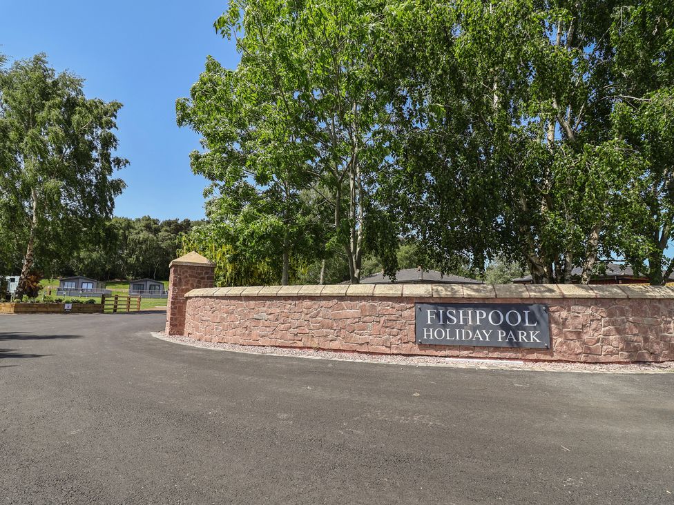 The entrance to Fishpool Holiday Park with trees and a sign in the foreground