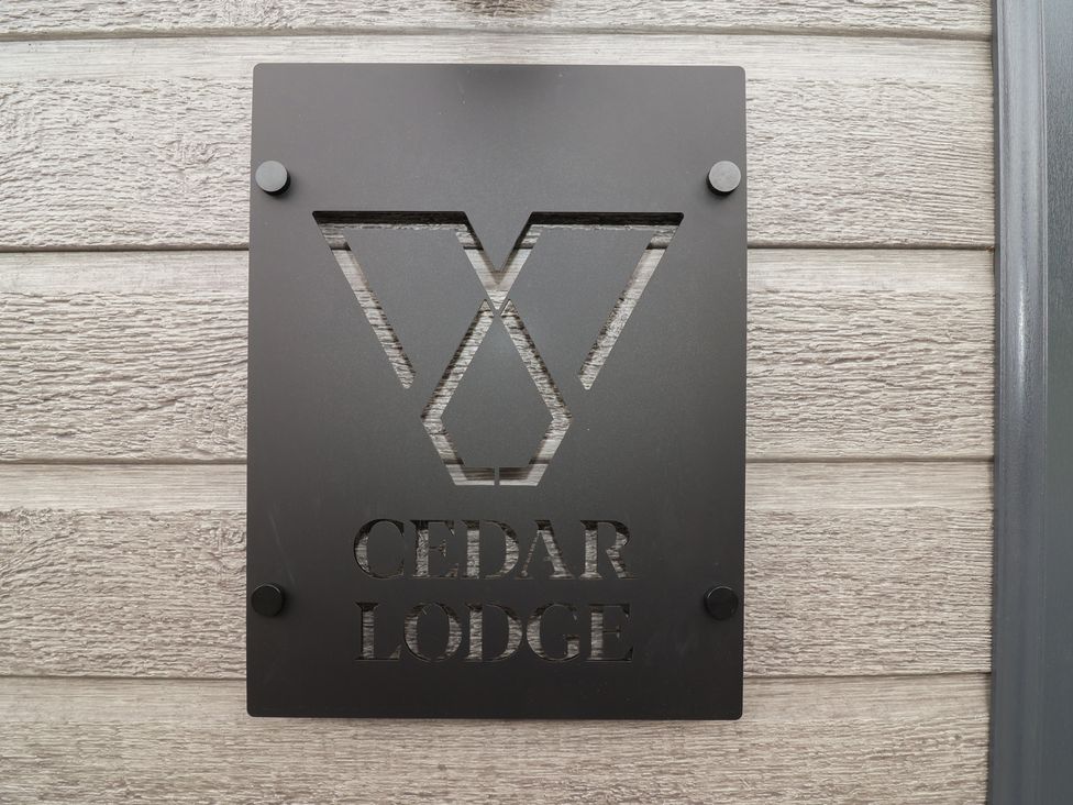 A sign for Cedar Lodge on a wooden wall at Cedar Lodge 3 Bedrooms Delamere
