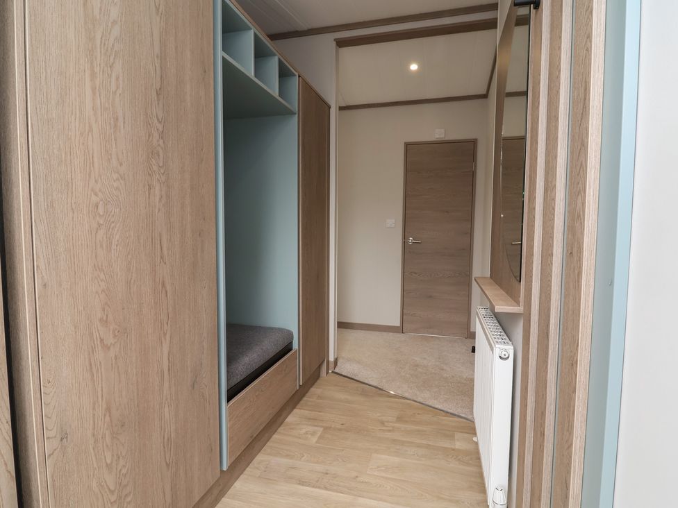 A hallway with a storage unit and mirror at Cedar Lodge 3 Bedrooms Delamere