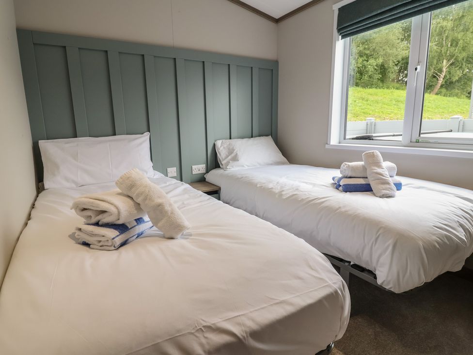 A bedroom with two single beds and towels at Cedar Lodge 3 Bedrooms Delamere
