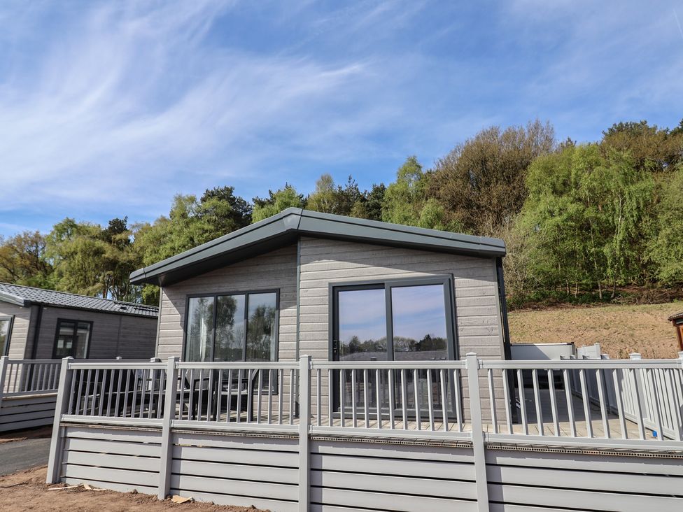A cabin with large windows and a deck at No.11 - Cedar Lodge in Delamere