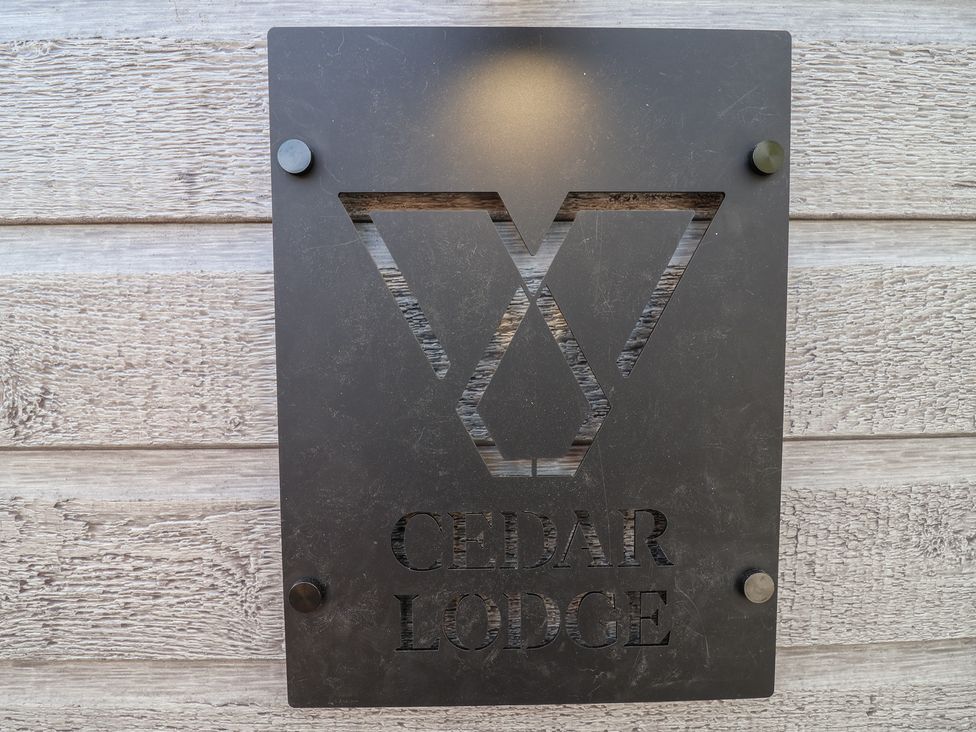 A sign displaying the name Cedar Lodge mounted outdoors at No.11 - Cedar Lodge in Delamere