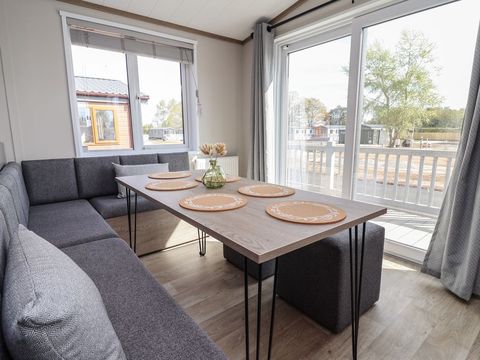 A dining room with a table and sofa at No.11 - Cedar Lodge in Delamere