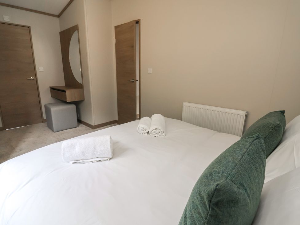 A bedroom with a bed and towels at No.11 - Cedar Lodge in Delamere