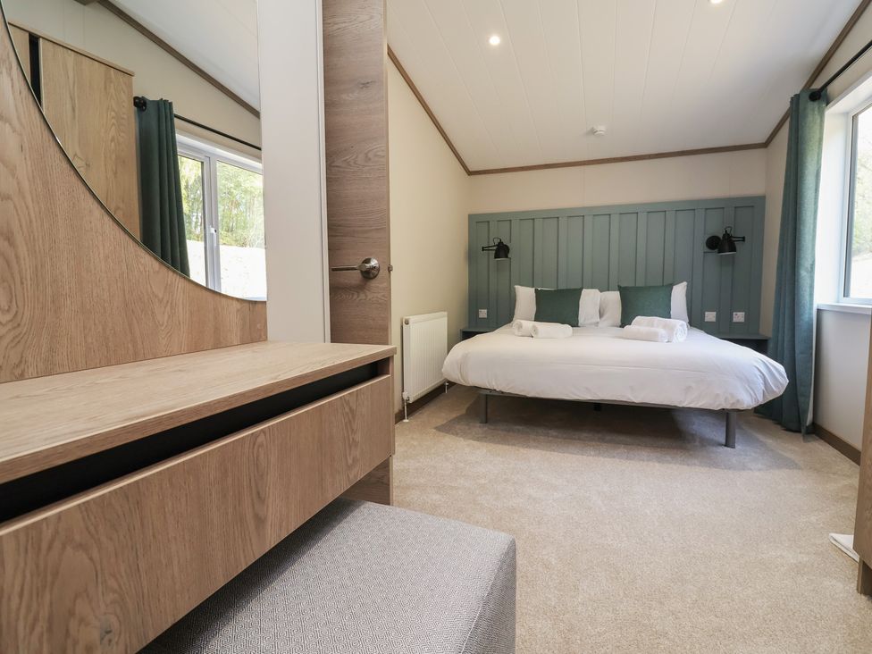 A bedroom with a bed and dresser at No.11 - Cedar Lodge in Delamere