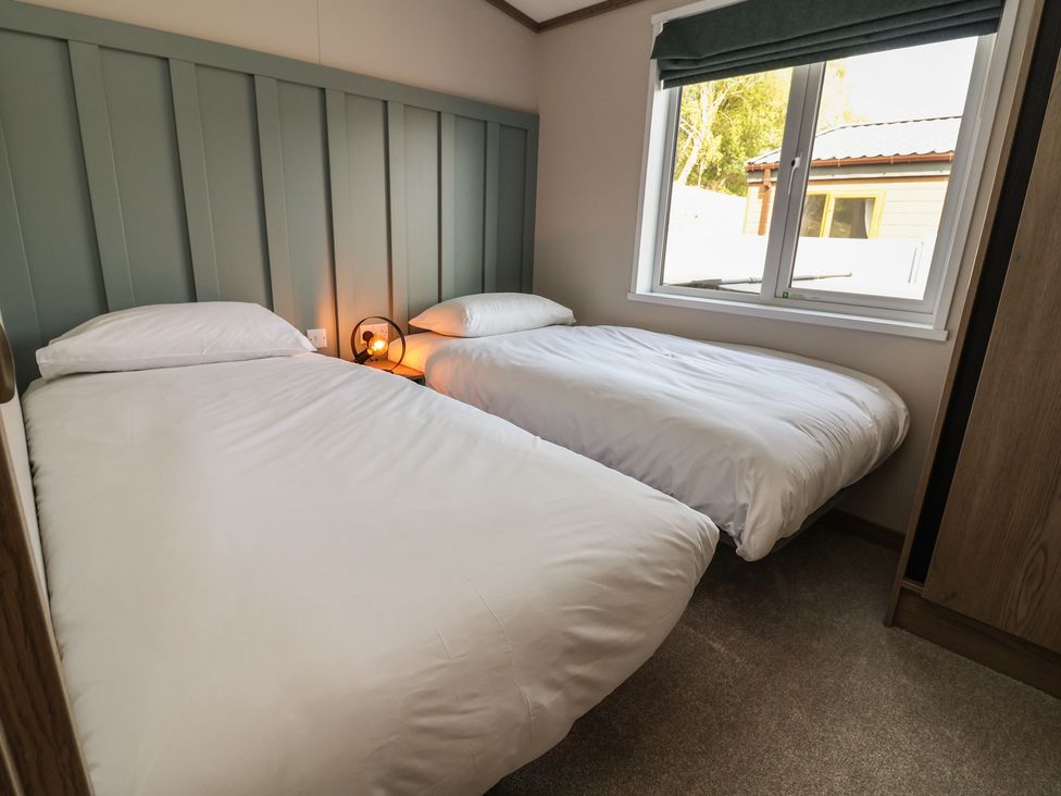 A bedroom with two beds and a window at No.11 - Cedar Lodge in Delamere