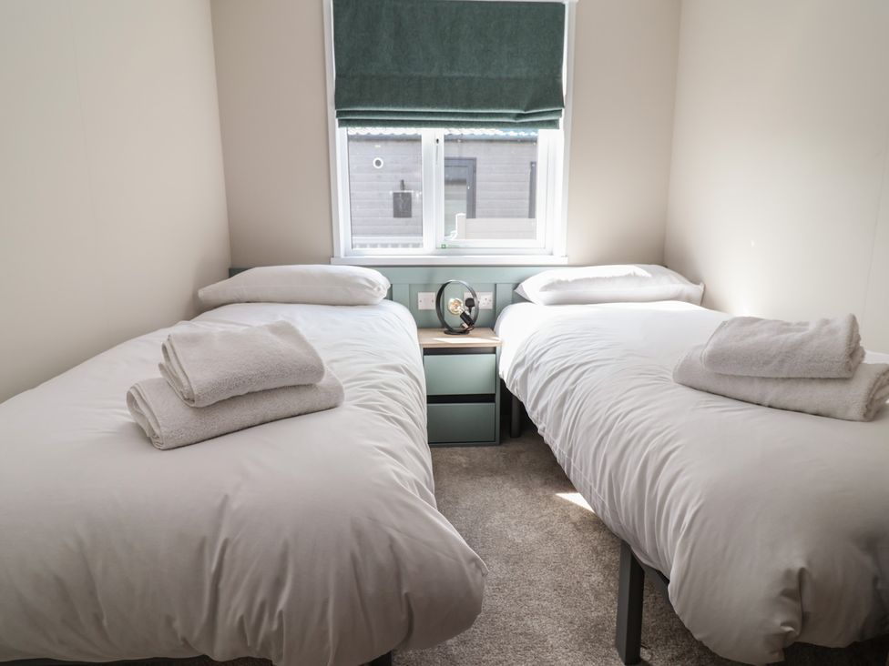 A bedroom with two single beds and a nightstand at No.11 - Cedar Lodge in Delamere