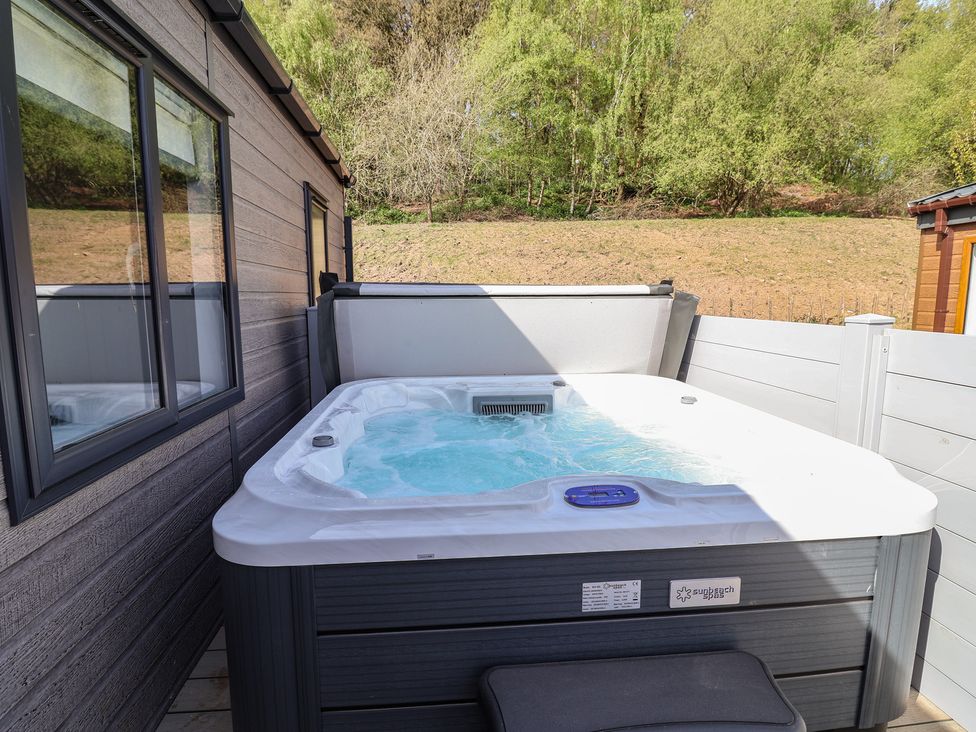 A hot tub outside with trees and a wooden wall at No.11 - Cedar Lodge in Delamere