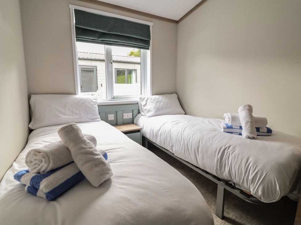 A bedroom with two single beds and towels at Cedar Lodge 3 Bedrooms with hot tub in Delamere