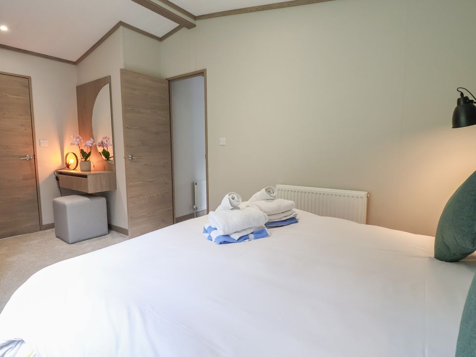 A bedroom with a bed and towels arranged on it at Cedar Lodge 3 Bedrooms with hot tub, Delamere