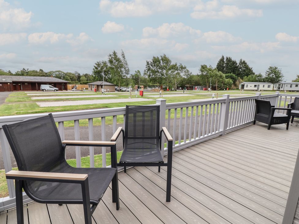 A deck with chairs overlooking a grassy area at Cedar Lodge 3 Bedrooms with hot tub Delamere