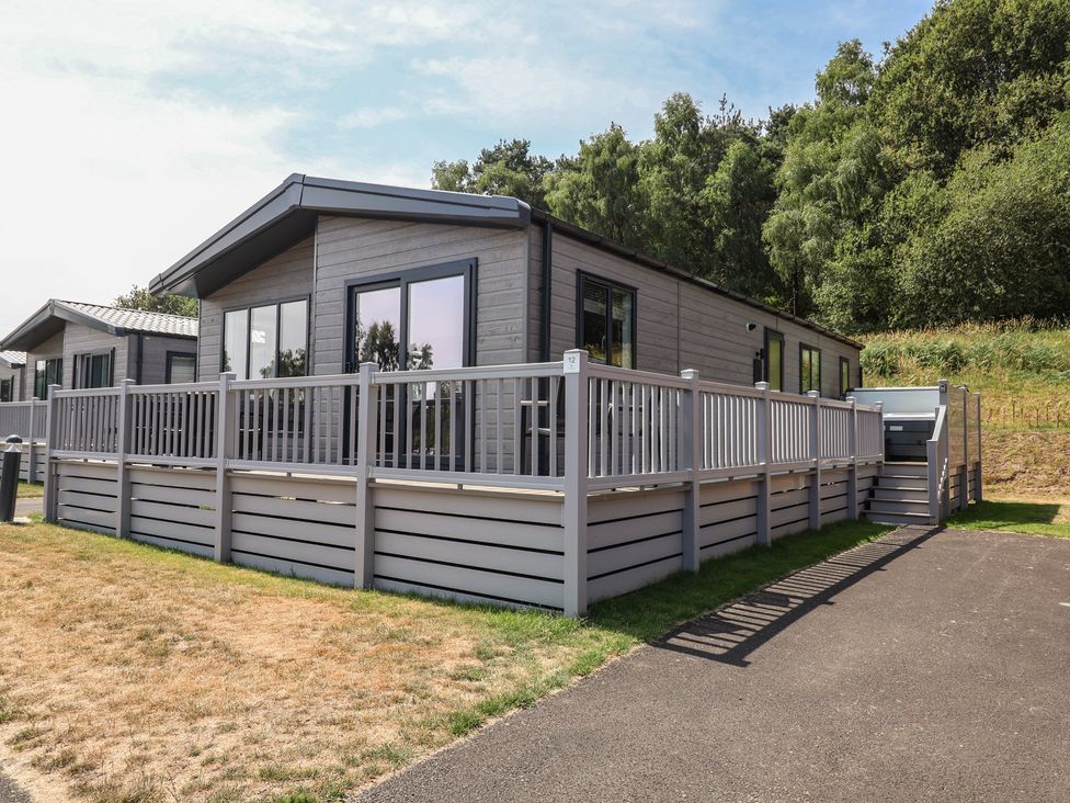 A log cabin with a decking area at Cedar Lodge 3 Bedrooms with hot tub Delamere