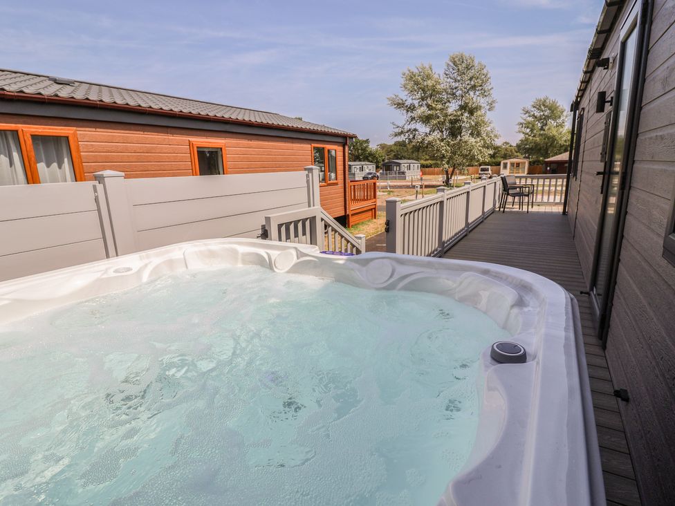 A hot tub on a wooden deck at Cedar Lodge 3 Bedrooms with hot tub in Delamere