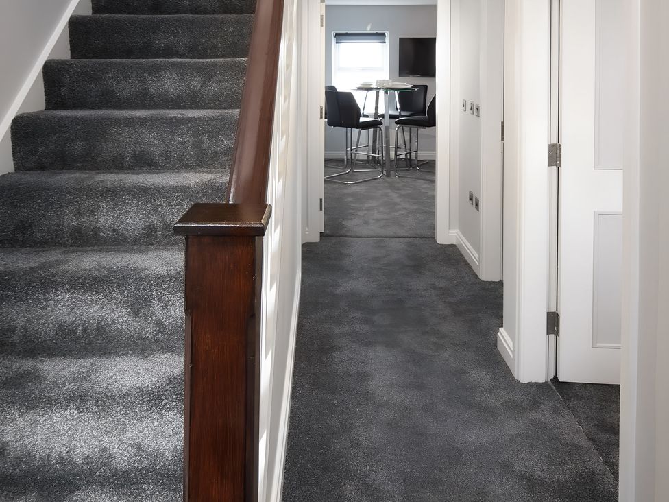 A hallway with stairs and a table with chairs at Apartment 3 in Blackpool