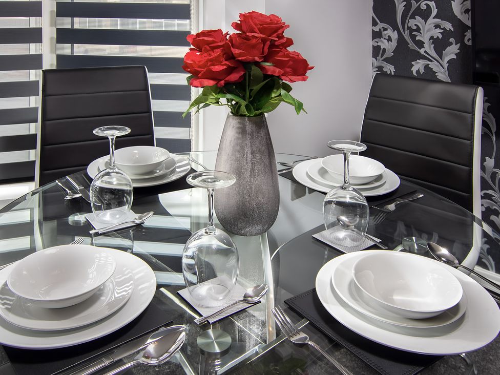 A dining table with black chairs and white plates at Apartment 2 in Blackpool