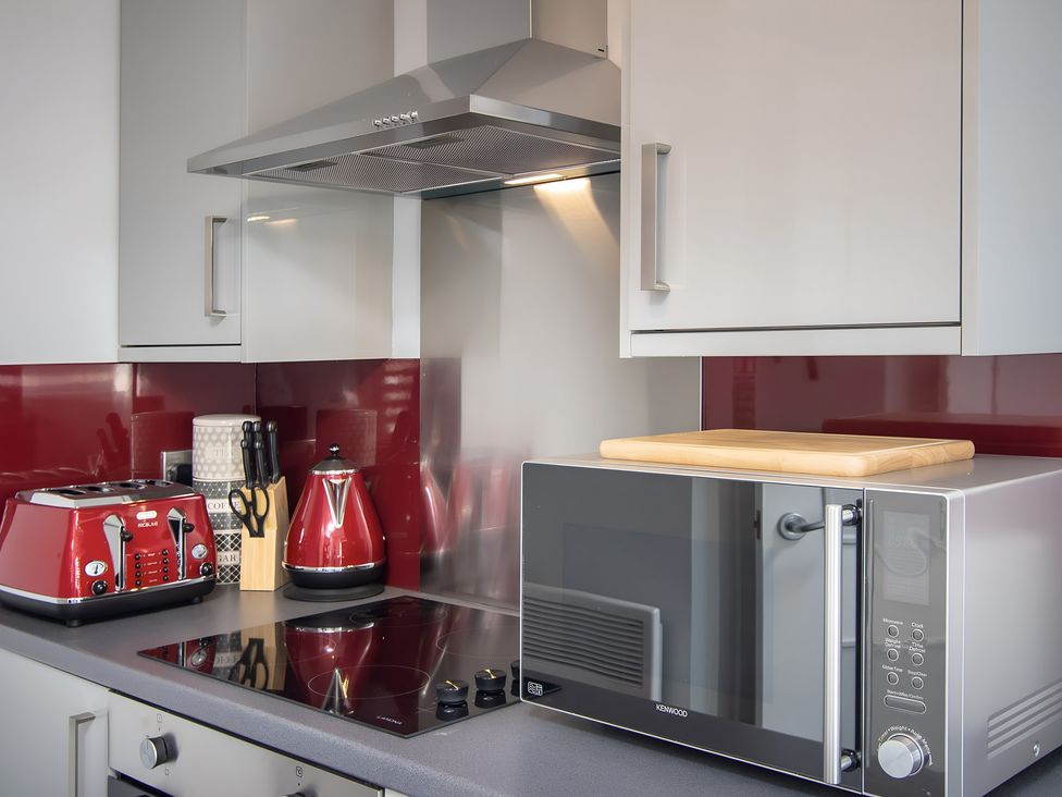 A kitchen with a microwave, toaster, kettle and induction cooktop at Apartment 2 in Blackpool
