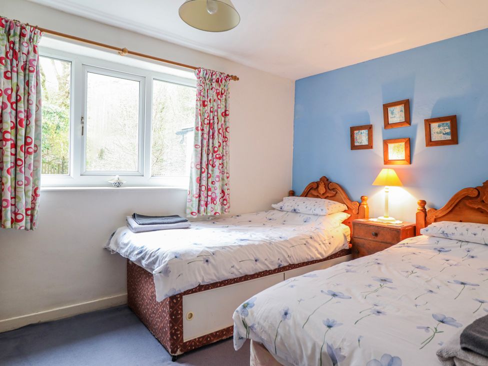 A bedroom with two beds and a lamp on a nightstand at 12 Glyn Terrace Borth-Y-Gest