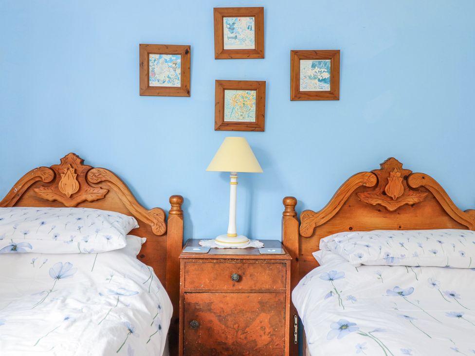 A bedroom with two beds and a lamp on a nightstand at 12 Glyn Terrace Borth-Y-Gest