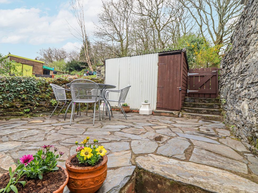 A garden with a table and chairs near a shed at 12 Glyn Terrace Borth-Y-Gest