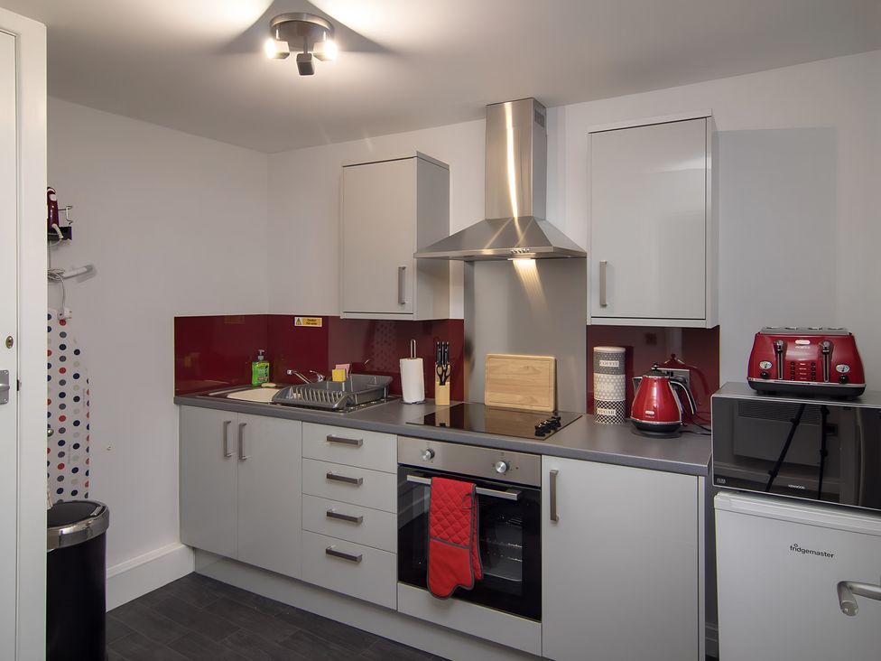 A kitchen featuring cabinets, a stove, and a sink at Apartment 1, Blackpool