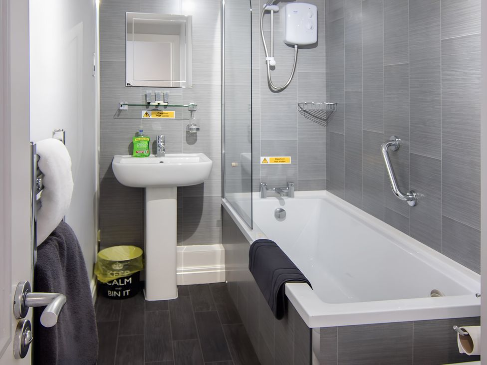 A bathroom with a bathtub and sink at Apartment 1 in Blackpool