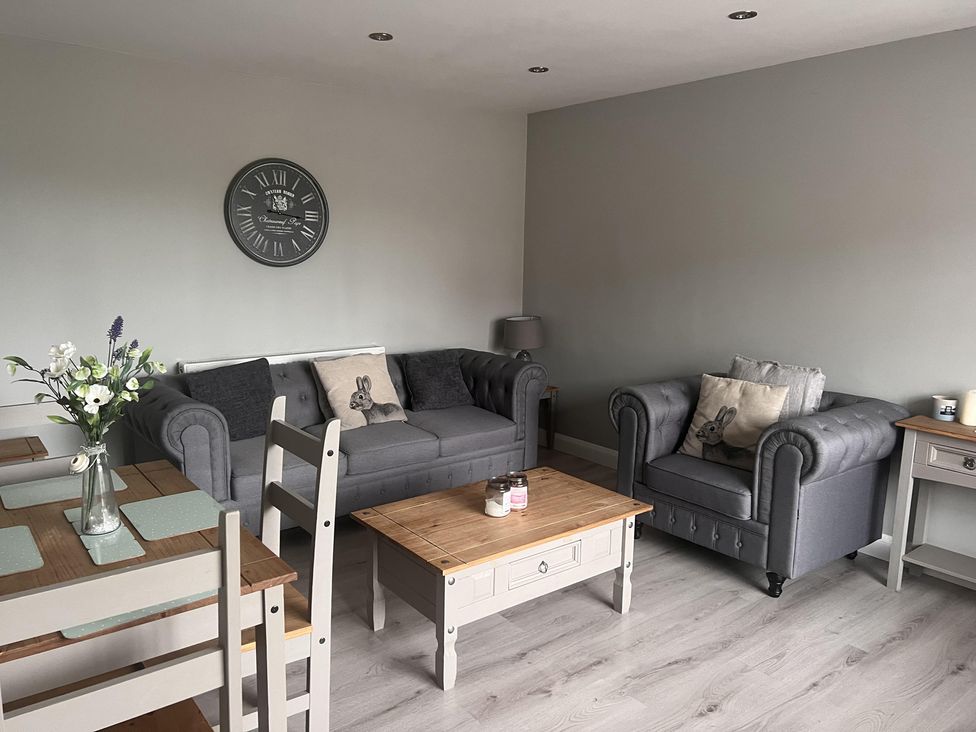 A living room with a sofa, armchair, coffee table, and dining area at 43 Goose Green Road in King's Lynn