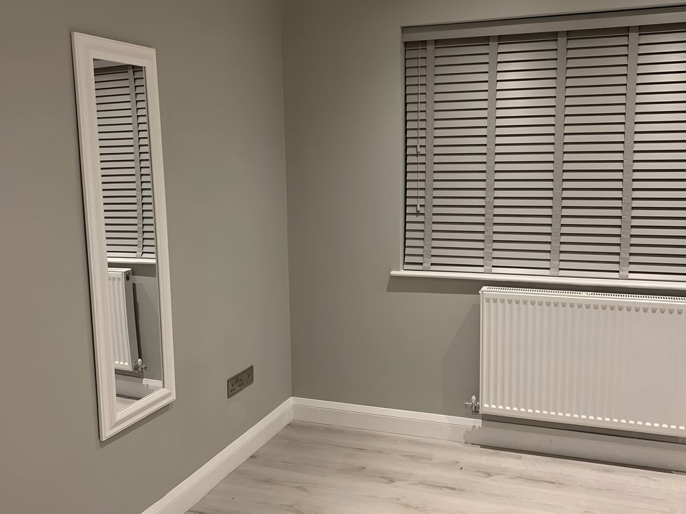 A bedroom with a mirror and window at 43 Goose Green Road in King's Lynn