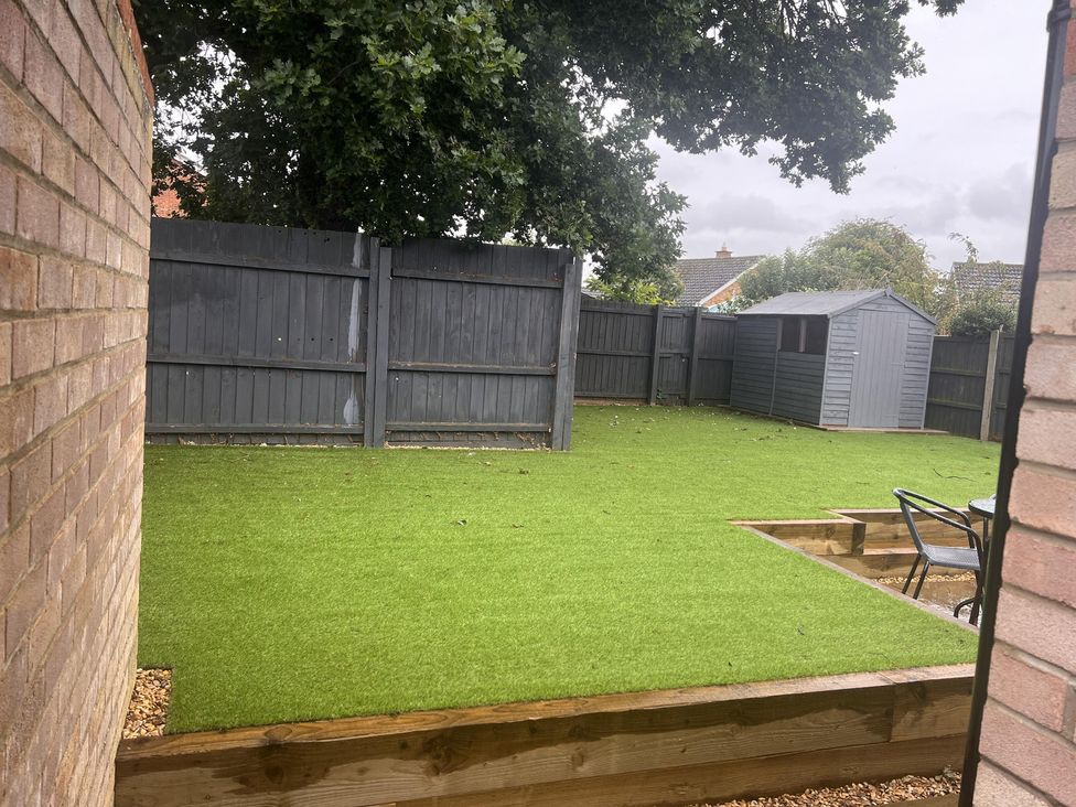 A garden with artificial grass, a shed, and a fenced area at 43 Goose Green Road in King's Lynn