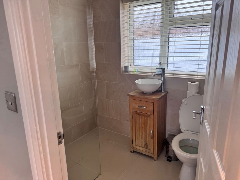 A bathroom with a shower, toilet, sink, and cabinet at 15 Lamsey Lane, King's Lynn