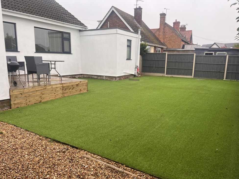 A garden with artificial grass, patio, table, chairs, and barbecue at 15 Lamsey Lane in King's Lynn