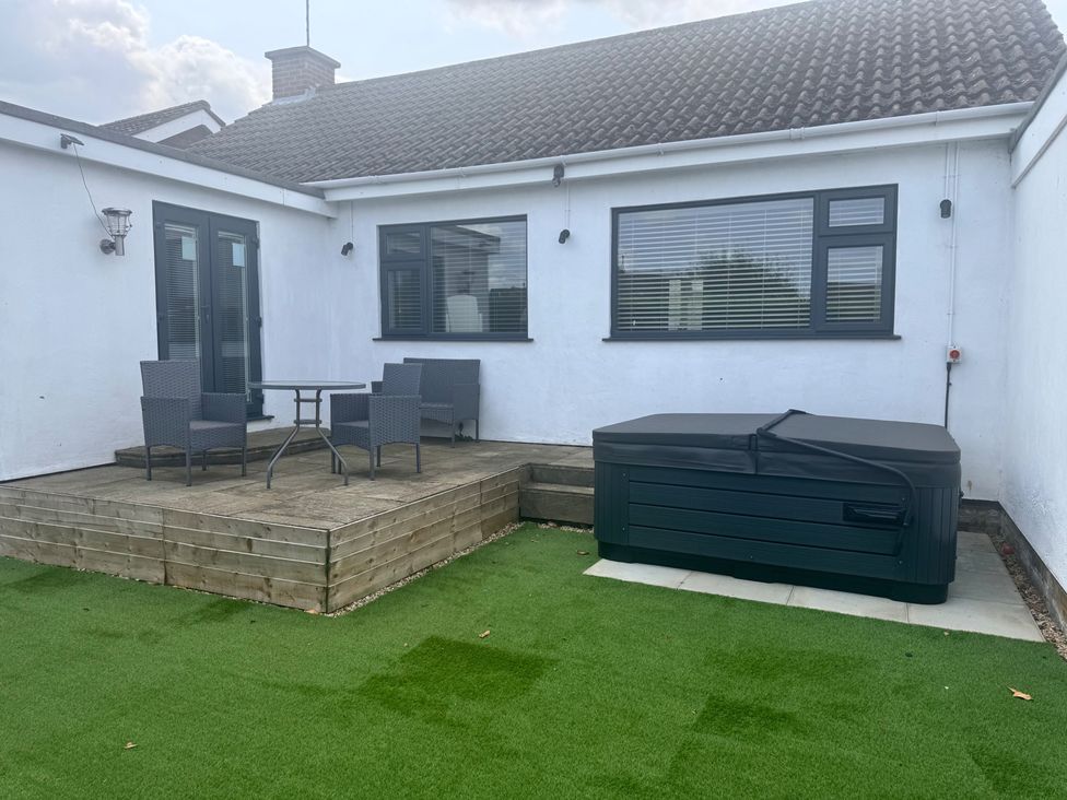 An outdoor area with a table and chairs next to a hot tub at 15 Lamsey Lane King's Lynn