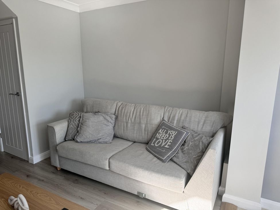 A living room with a sofa and cushion at 22 Sandringham Drive in King's Lynn
