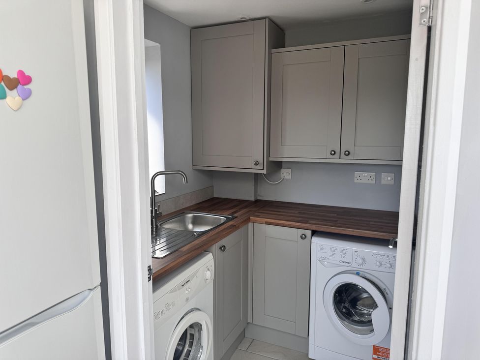 A laundry room with a fridge and washing machine at 22 Sandringham Drive in King's Lynn