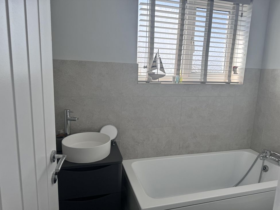 A bathroom with a bathtub and sink at 22 Sandringham Drive in King's Lynn