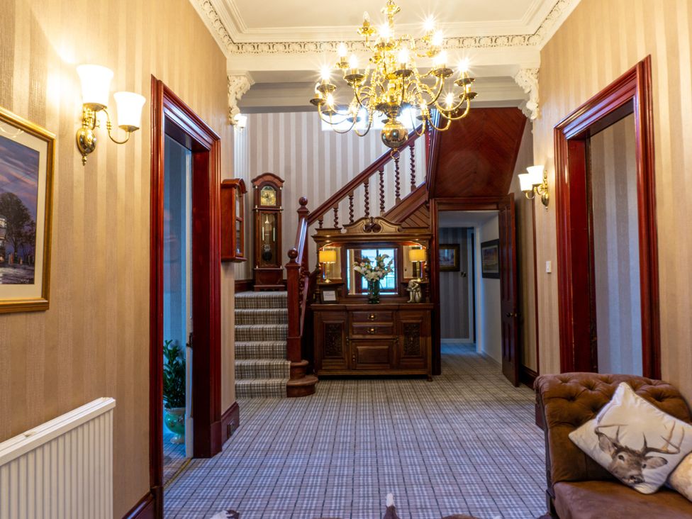 A hallway with a chandelier and staircase at Newton Manor House in Cupar
