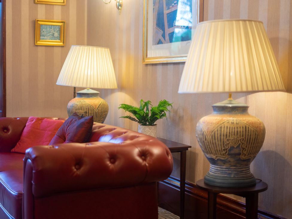 A living room with a red sofa and lamps at Newton Manor House in Cupar