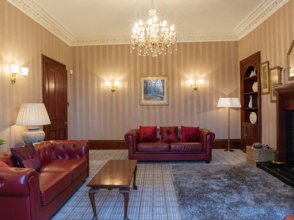 A living room with a sofa, coffee table and lamp at Newton Manor House in Cupar