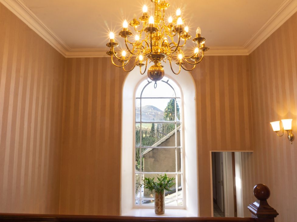 A staircase with a chandelier and a large window at Newton Manor House in Cupar