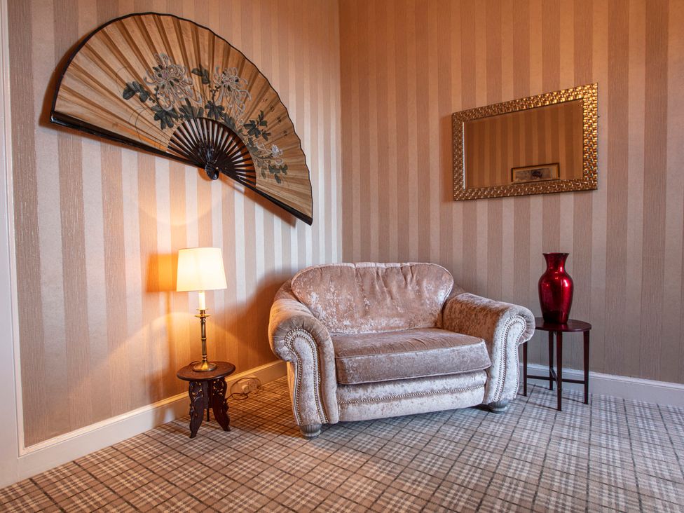A living room with a fan, mirror, and sofa at Newton Manor House in Cupar