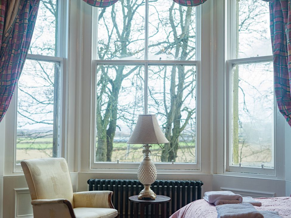 A bedroom with a lamp and armchair at Newton Manor House in Cupar