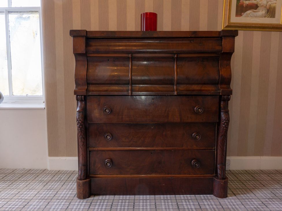 A chest of drawers with a red glass on top at Newton Manor House in Cupar